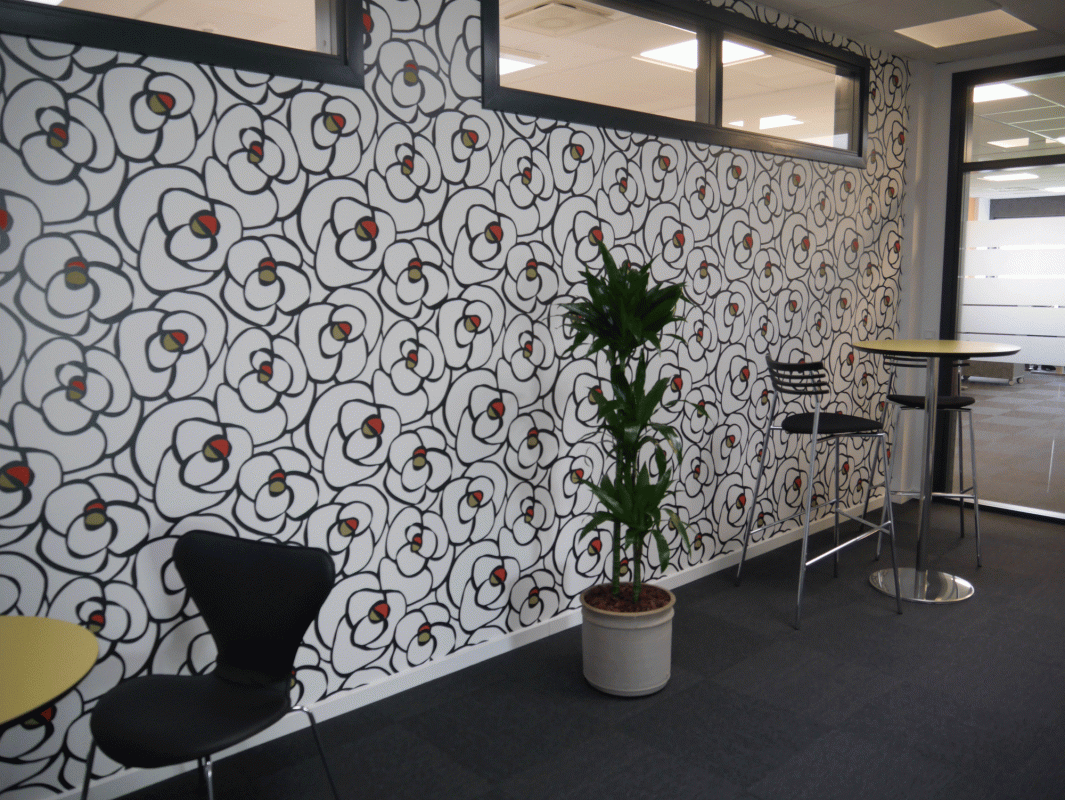 virksomhedsindretning med mønstreret tapet sorte stole, runde borde og plante