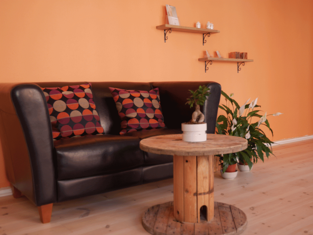 kontorindretning med sort sofa og rundt træbord hos sorø akupunktur