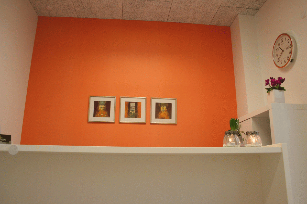 kontorindretning med orange væg og malerier