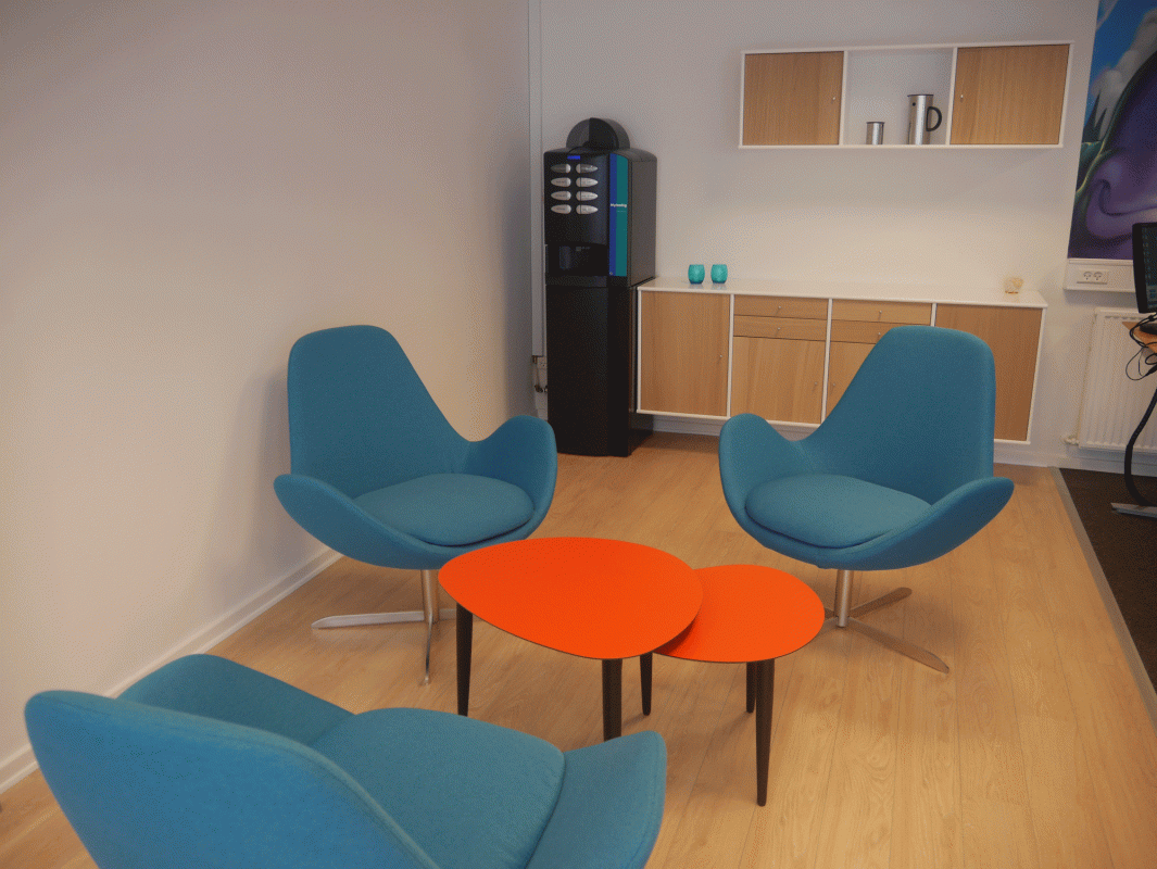 kontorindrettet kaffehjørne med blå lænestole og orange kaffeborde hos Nybolig